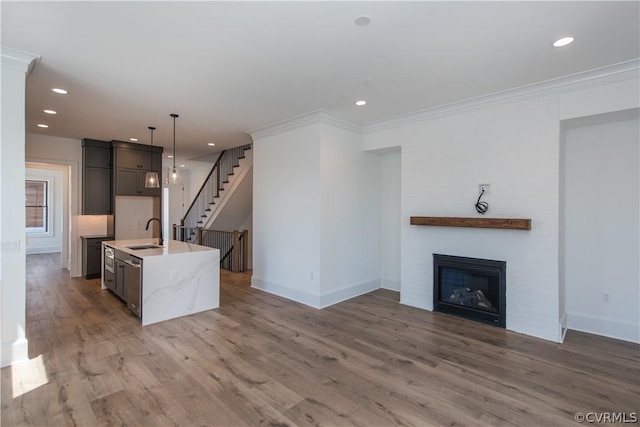 kitchen with a glass covered fireplace, crown molding, light wood-style floors, and a sink