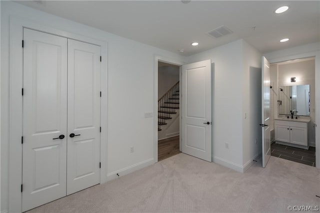 unfurnished bedroom with baseboards, visible vents, carpet floors, recessed lighting, and a sink