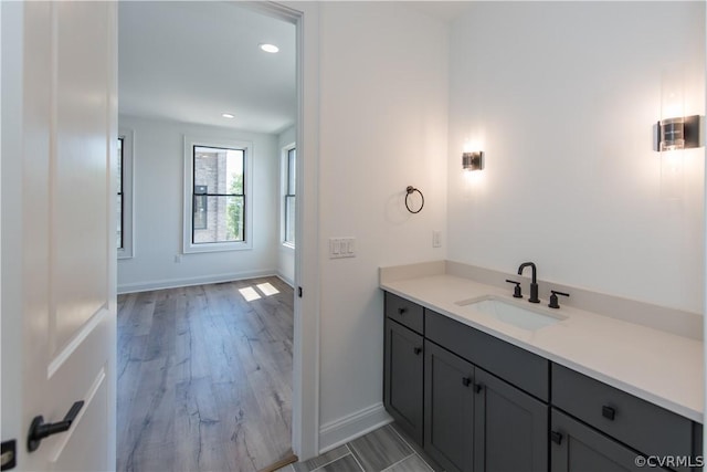 bathroom featuring recessed lighting, vanity, baseboards, and wood finished floors