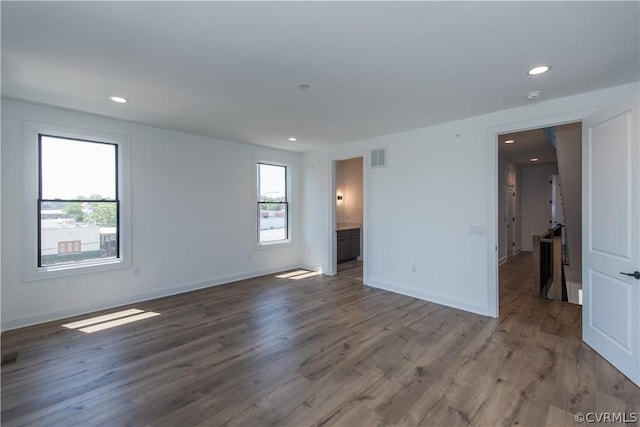 empty room with wood finished floors, baseboards, and a wealth of natural light