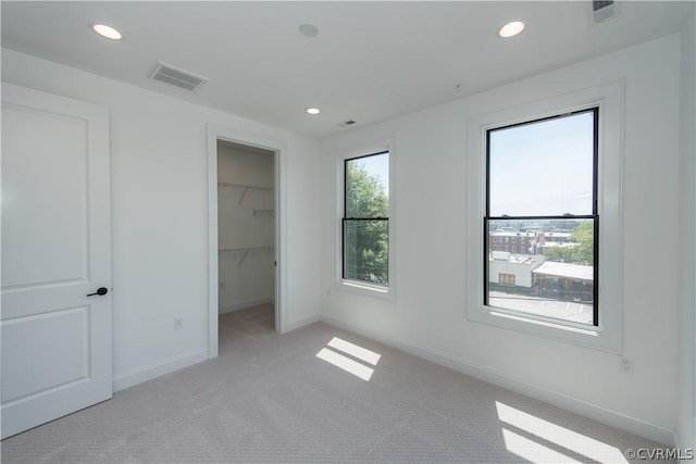 unfurnished bedroom with visible vents, light carpet, recessed lighting, baseboards, and a spacious closet