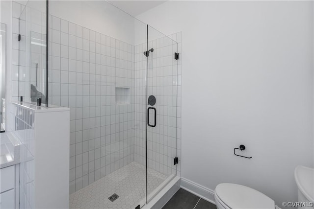 bathroom with tile patterned floors, a stall shower, toilet, and baseboards