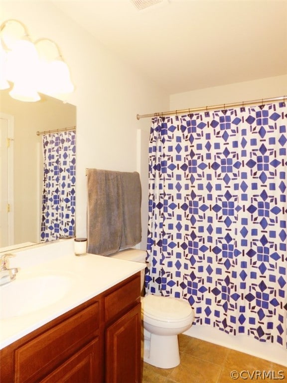 bathroom with tile flooring, toilet, and vanity