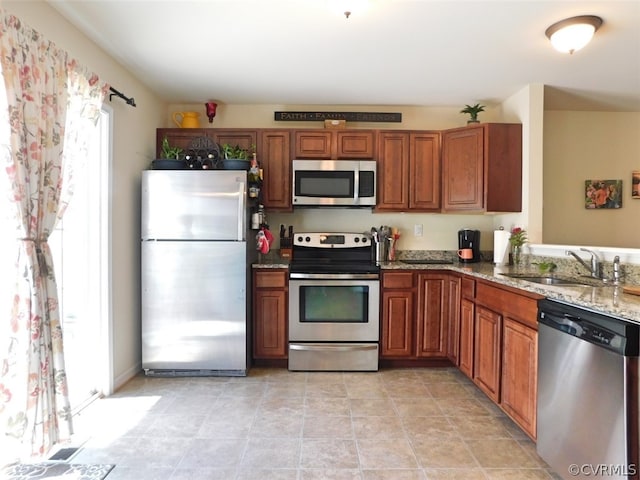 kitchen featuring appliances with stainless steel finishes, sink, light stone countertops, and light tile floors