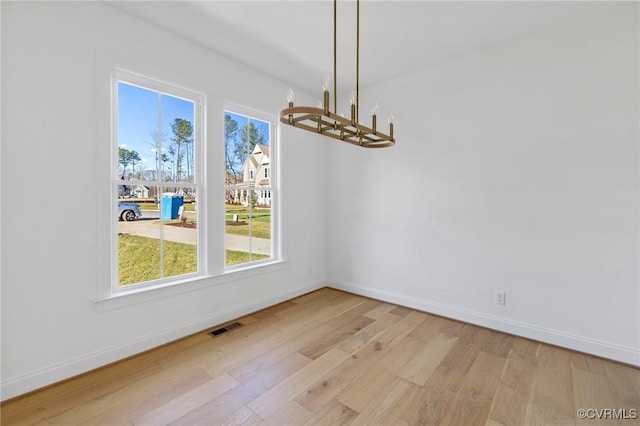 unfurnished dining area featuring a chandelier and light wood-type flooring