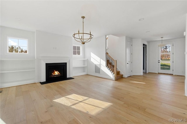 unfurnished living room with light hardwood / wood-style flooring and a notable chandelier