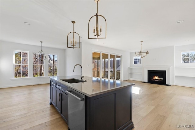 kitchen featuring a kitchen island with sink, sink, dishwasher, and light wood-type flooring