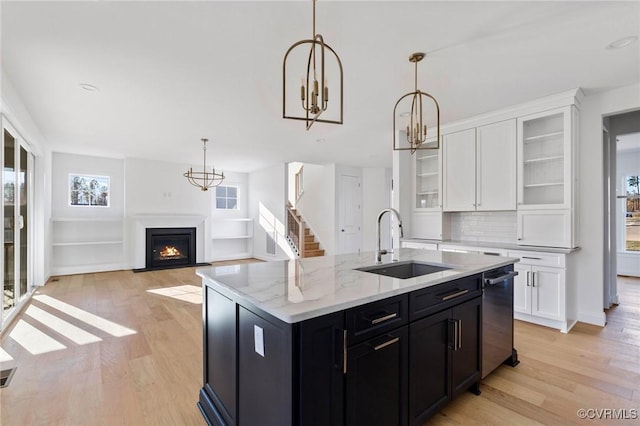 kitchen with a wealth of natural light, light hardwood / wood-style flooring, white cabinets, and a kitchen island with sink