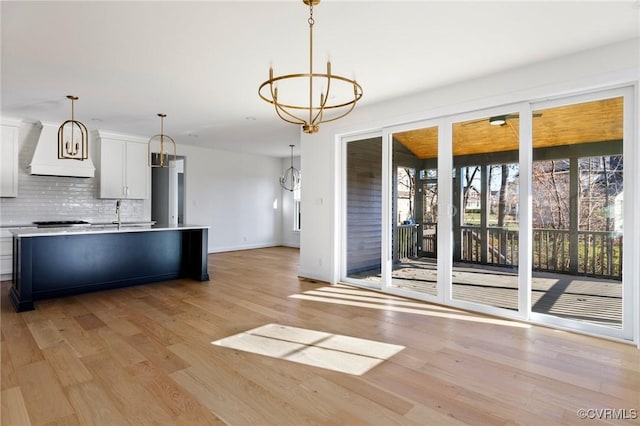 kitchen featuring decorative backsplash, decorative light fixtures, light hardwood / wood-style flooring, white cabinets, and a chandelier