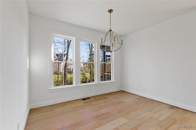 unfurnished dining area with a notable chandelier, light wood-type flooring, and a wealth of natural light