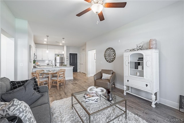 living room featuring ceiling fan, sink, and dark wood-type flooring