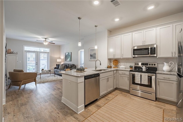 kitchen featuring sink, white cabinets, decorative light fixtures, and appliances with stainless steel finishes