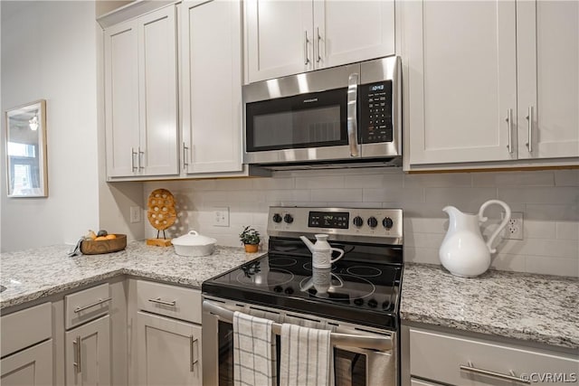 kitchen with backsplash, light stone counters, white cabinetry, and stainless steel appliances