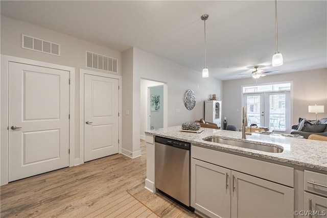 kitchen with light stone countertops, sink, light hardwood / wood-style flooring, stainless steel dishwasher, and pendant lighting