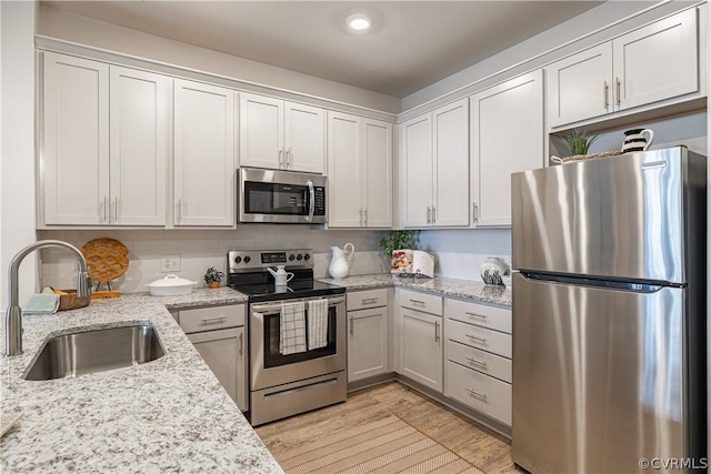 kitchen featuring white cabinets, light stone counters, sink, and stainless steel appliances