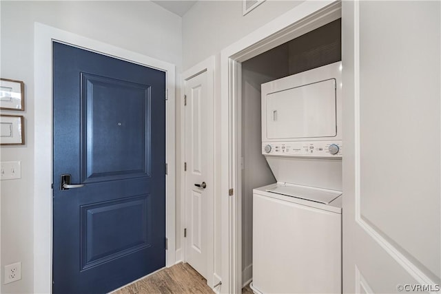 laundry area featuring wood-type flooring and stacked washer and clothes dryer