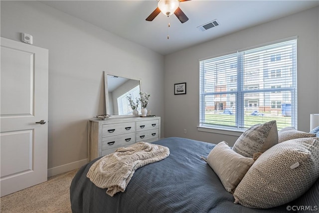 bedroom featuring light colored carpet, multiple windows, and ceiling fan