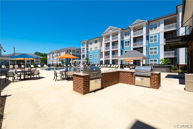 view of patio / terrace featuring area for grilling, a community pool, and exterior kitchen