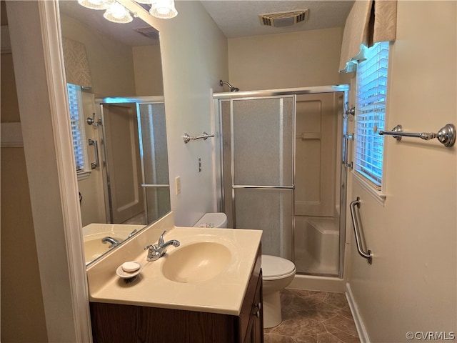 bathroom featuring tile patterned flooring, vanity, toilet, and a shower with door