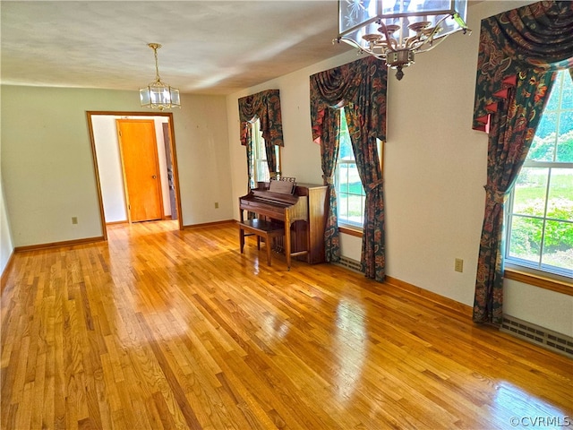 interior space with light hardwood / wood-style flooring, a healthy amount of sunlight, and an inviting chandelier