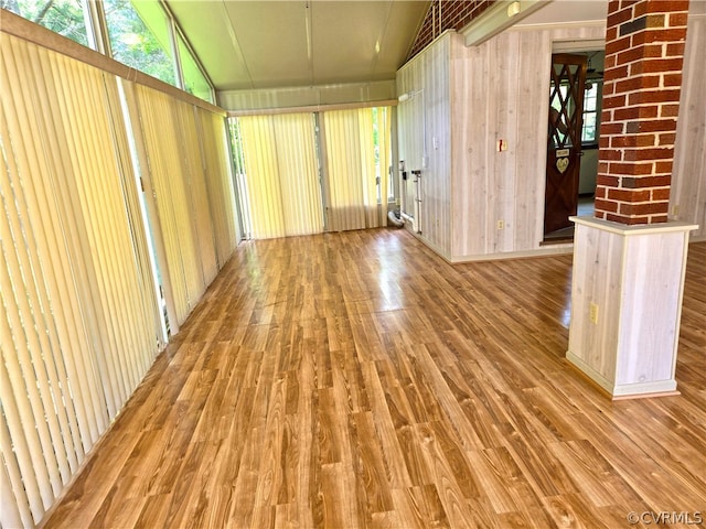 empty room with lofted ceiling, hardwood / wood-style flooring, and wooden walls