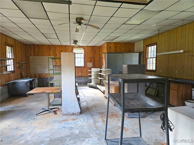 kitchen with a paneled ceiling, wooden walls, and ceiling fan