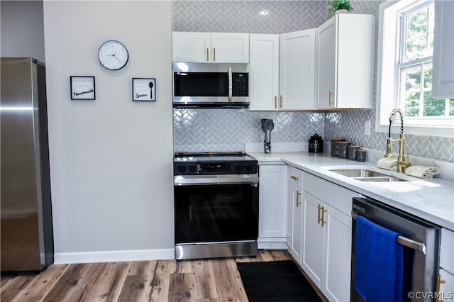 kitchen with sink, white cabinets, light hardwood / wood-style flooring, and appliances with stainless steel finishes