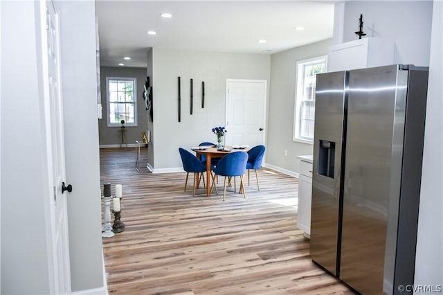 kitchen featuring stainless steel fridge with ice dispenser, white cabinetry, light hardwood / wood-style flooring, and plenty of natural light