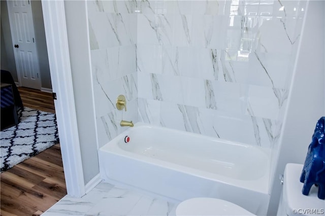 bathroom with bathing tub / shower combination, hardwood / wood-style floors, and toilet