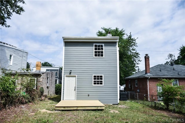 back of property featuring a deck and a lawn