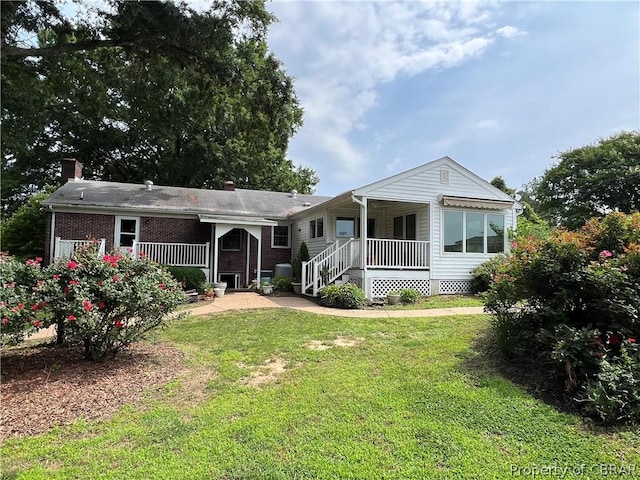 rear view of property featuring a yard and covered porch