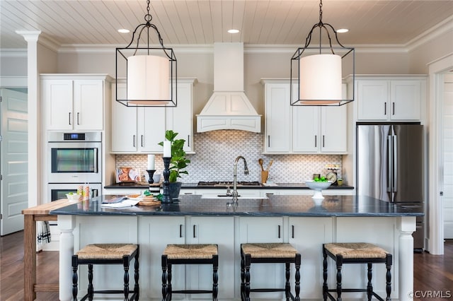 kitchen with decorative light fixtures, dark hardwood / wood-style flooring, custom range hood, and a kitchen island with sink