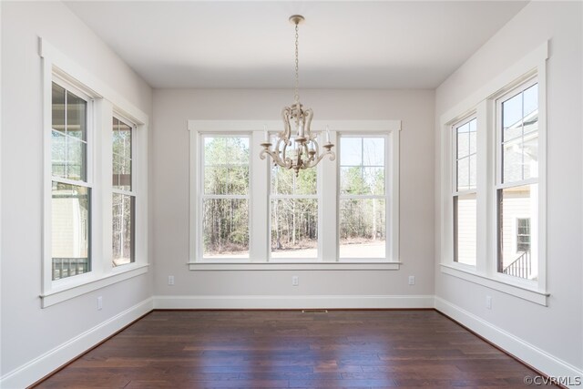 unfurnished dining area with wood-type flooring and an inviting chandelier