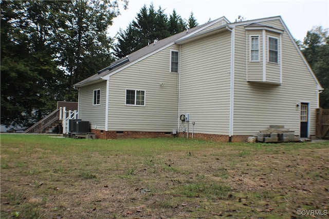 view of property exterior with central AC unit and a lawn