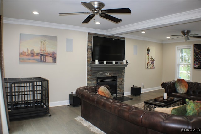 living room featuring hardwood / wood-style floors, ceiling fan, a stone fireplace, and crown molding