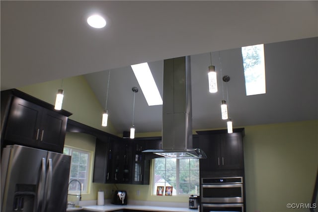 kitchen featuring stainless steel appliances, island range hood, hanging light fixtures, sink, and a skylight