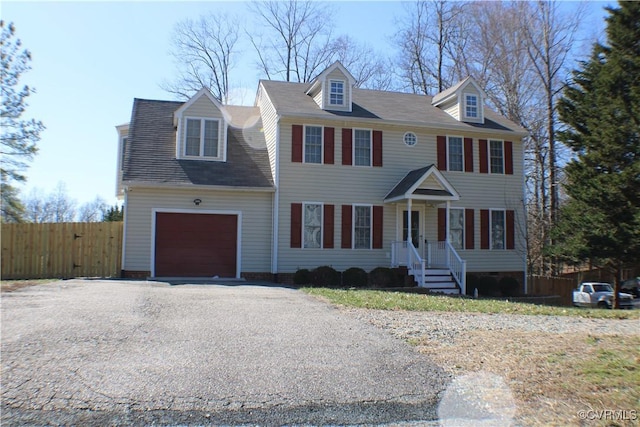 view of front facade with aphalt driveway, an attached garage, and fence