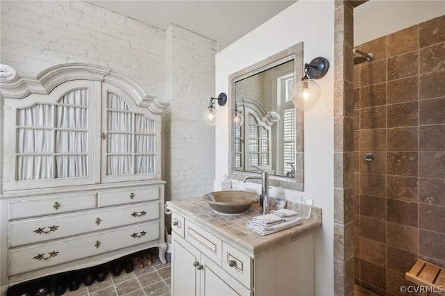 bathroom with a tile shower and vanity