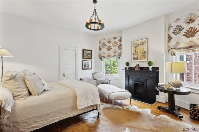 bedroom with light wood-type flooring, radiator, and an inviting chandelier