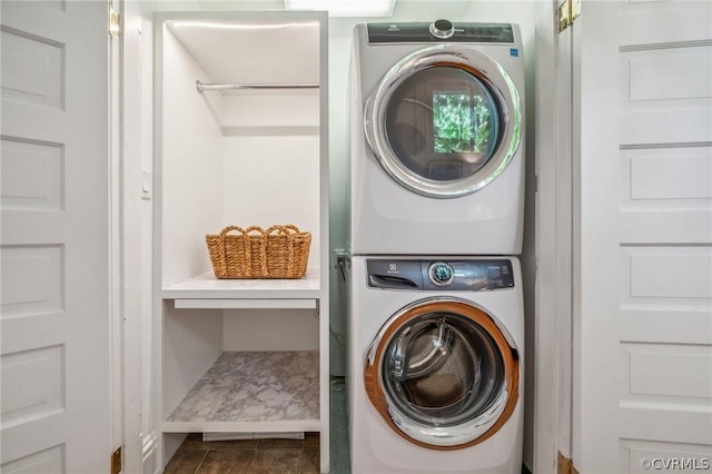 washroom featuring dark tile patterned floors and stacked washing maching and dryer