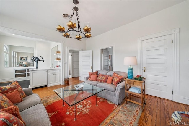 living room featuring light wood-type flooring, an inviting chandelier, and sink