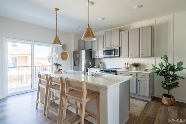 kitchen with sink, stainless steel appliances, dark hardwood / wood-style floors, gray cabinets, and a center island with sink