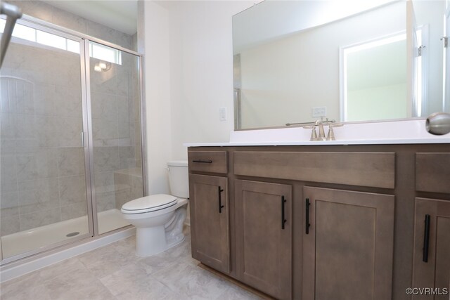 bathroom featuring toilet, vanity, and a shower with door