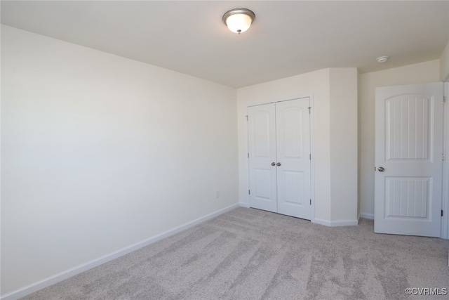 unfurnished bedroom with a closet and light colored carpet