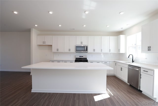 kitchen with dark wood-type flooring, appliances with stainless steel finishes, sink, and a center island