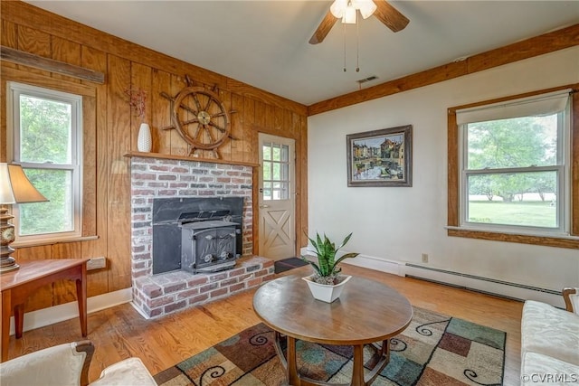 living area featuring a baseboard heating unit, wood finished floors, visible vents, and wood walls