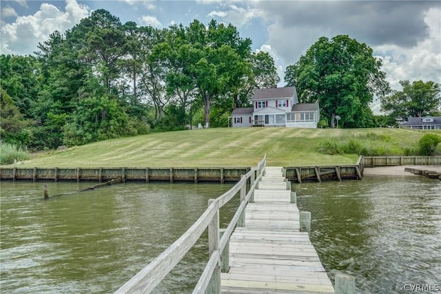 view of dock with a yard and a water view