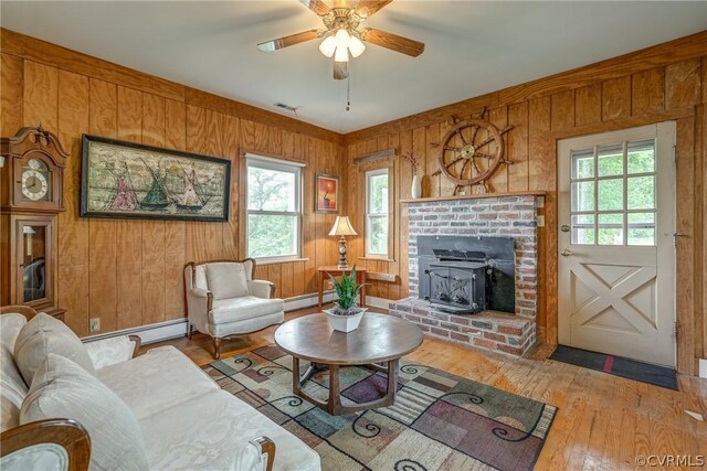 living room featuring a baseboard heating unit, wooden walls, ceiling fan, and hardwood / wood-style floors