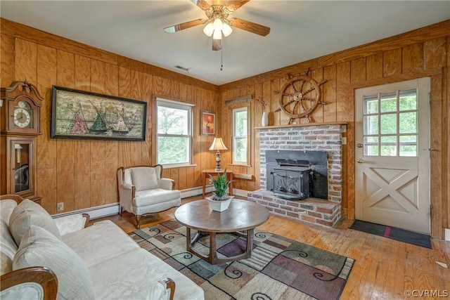 living room featuring visible vents, baseboard heating, hardwood / wood-style floors, and a ceiling fan