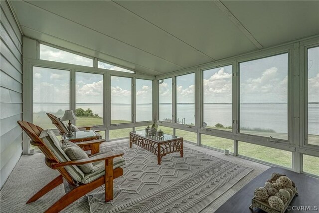 sunroom with vaulted ceiling and a water view